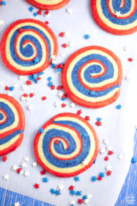 Patriotic pinwheel cookies are the perfect red, white and blue dessert for your holiday celebrations. These pinwheel cookies feature layered sugar cookie dough that is rolled with parchment paper, chilled and sliced before baking. If you want beautiful 4th of July cookies that are easy to transport and serve, try this soft pinwheel cookie recipe!
